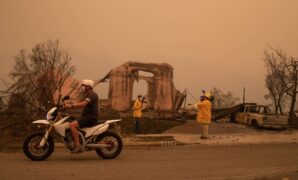 A man rides past journalists reporting on the aftermath of the Shady Fire in Santa Rosa, California, on Sept. 28, 2020.