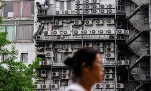 A woman walks past air-conditioning units on a building in Seoul on April 30.